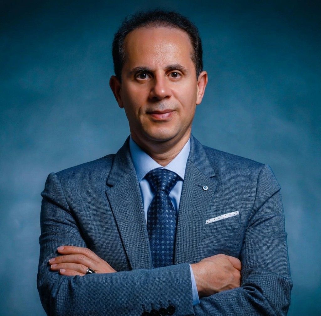 Professional headshot of Mohsen Bolouri, independent mortgage broker, wearing a suit and tie with arms crossed